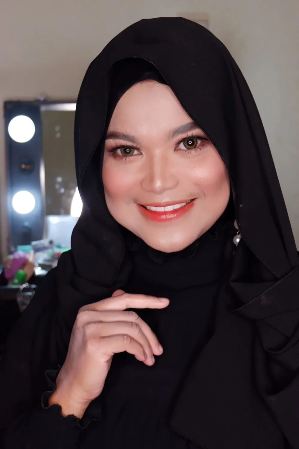 Mifta, makeup artist di balik TataSeptiyana Art, mengenakan hijab hitam di depan meja rias.